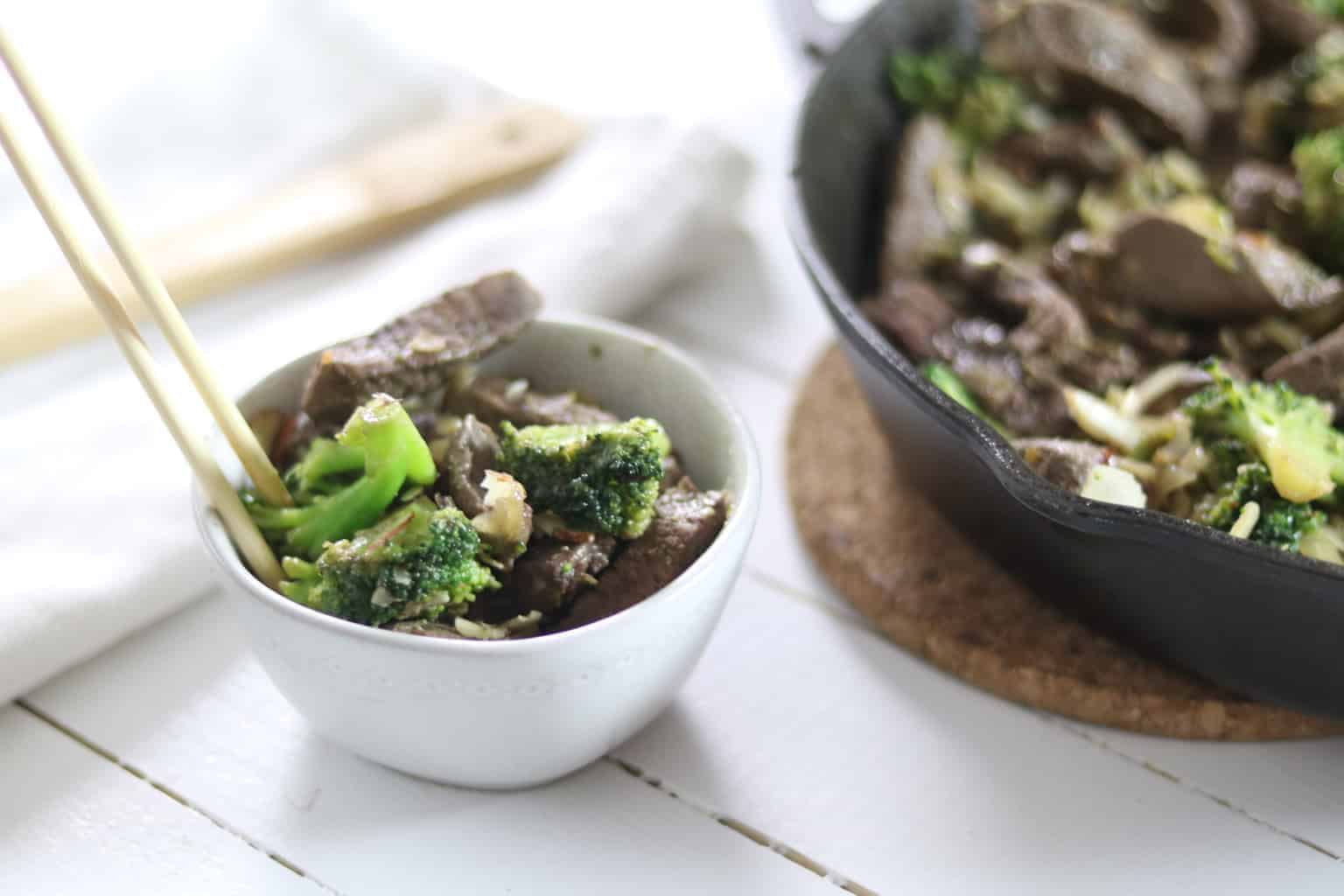 Broccoli and beef in a cast iron skillet and also in white bowl.