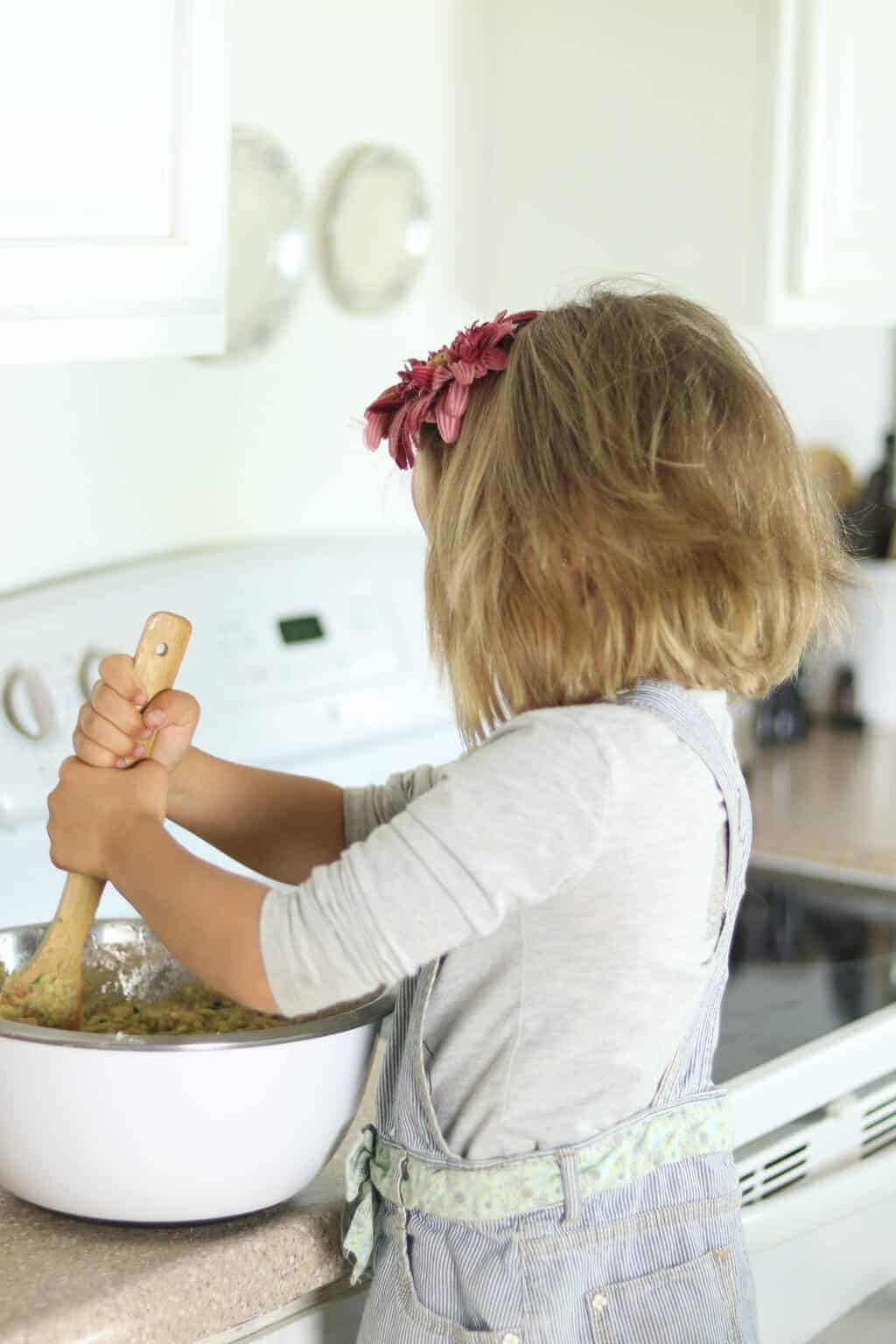 A little girl helping cook in the kitchen.