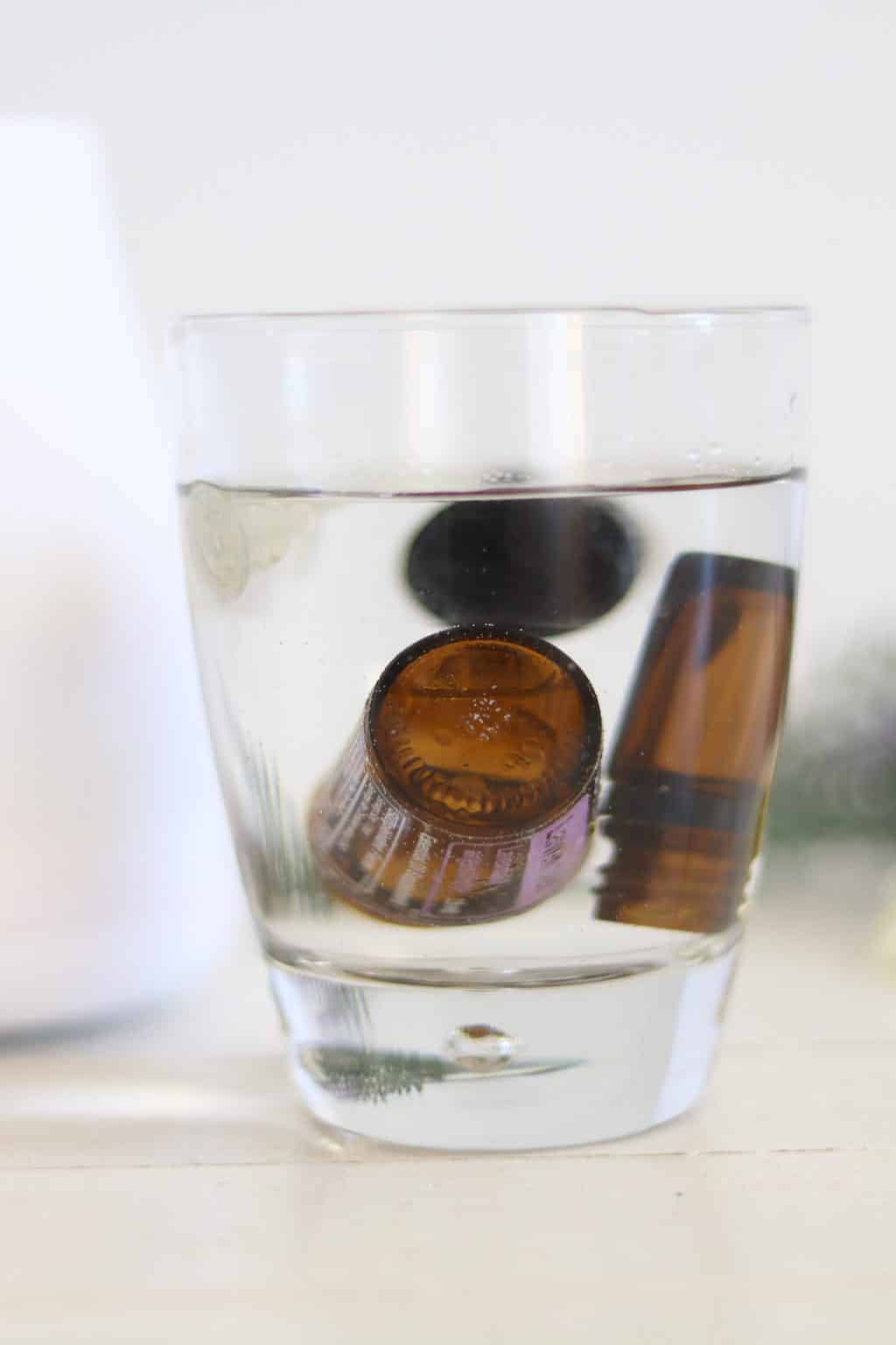 Empty essential oil bottles in a glass of water.