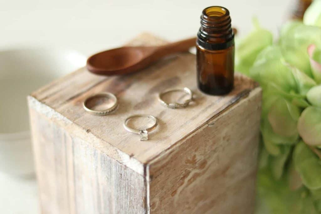 A DIY jewelry cleaner with 3 rings on a wooden cleaner box.