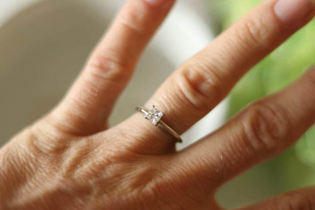 A clean, diamond ring with a white gold band on the ring finger.