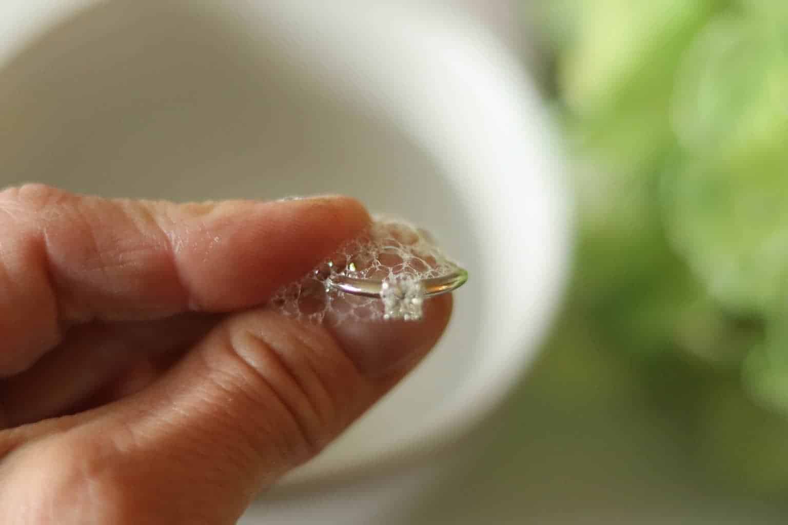 Holding cut diamond ring while cleaning with soap.