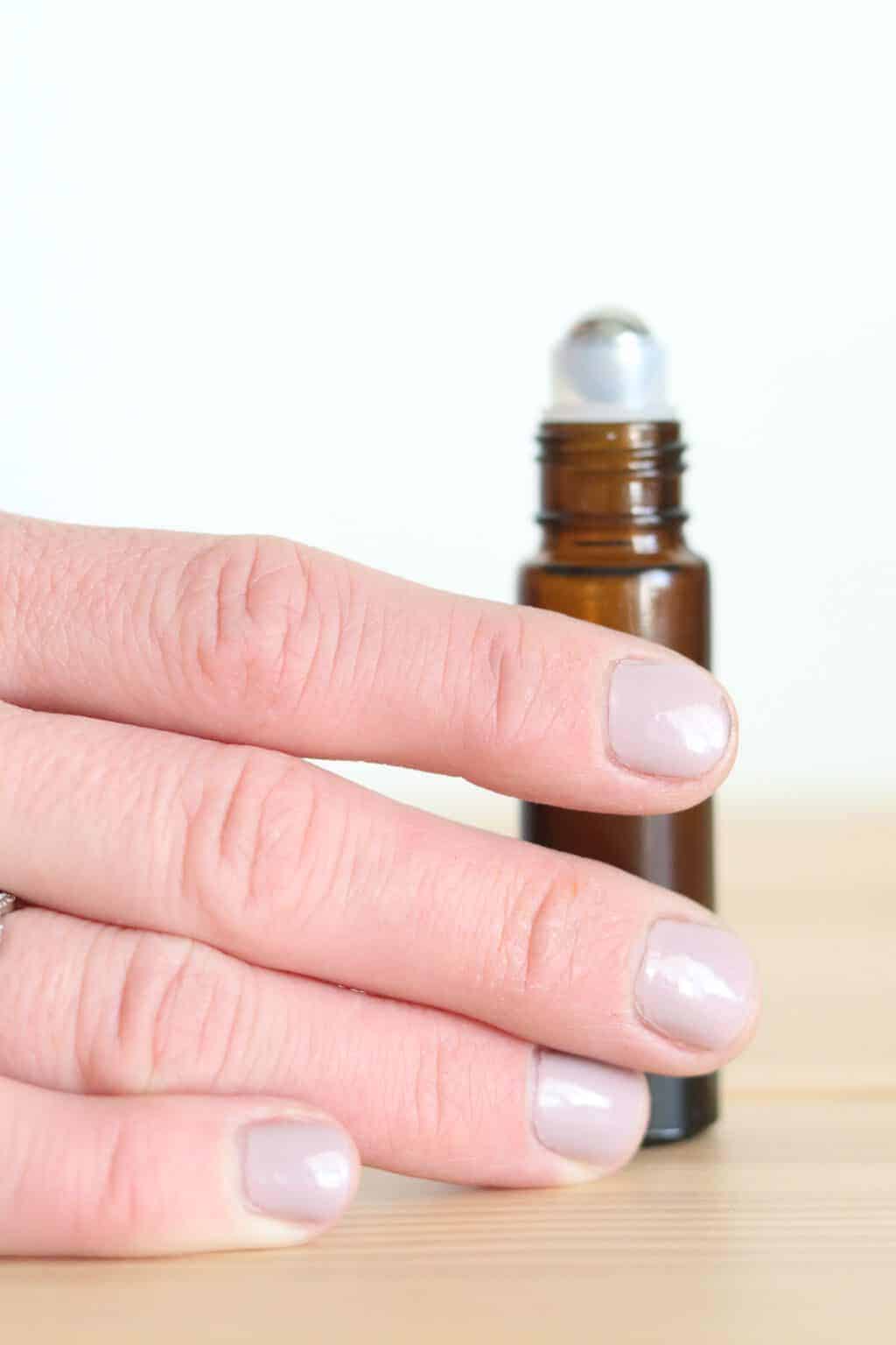 Women's hand and fingernails on roller bottle.