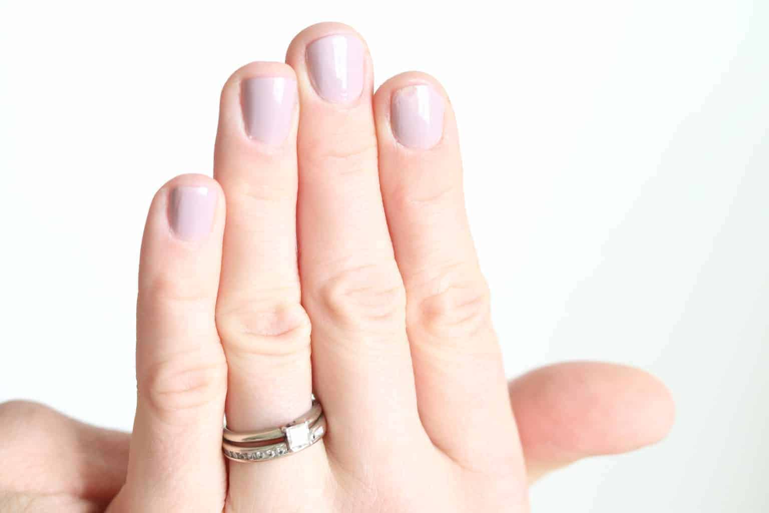 Women's hand with light pink painted nails.