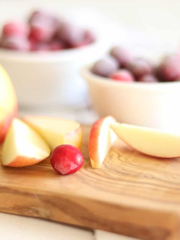 Several pieces of fruit on a wooden cutting board.