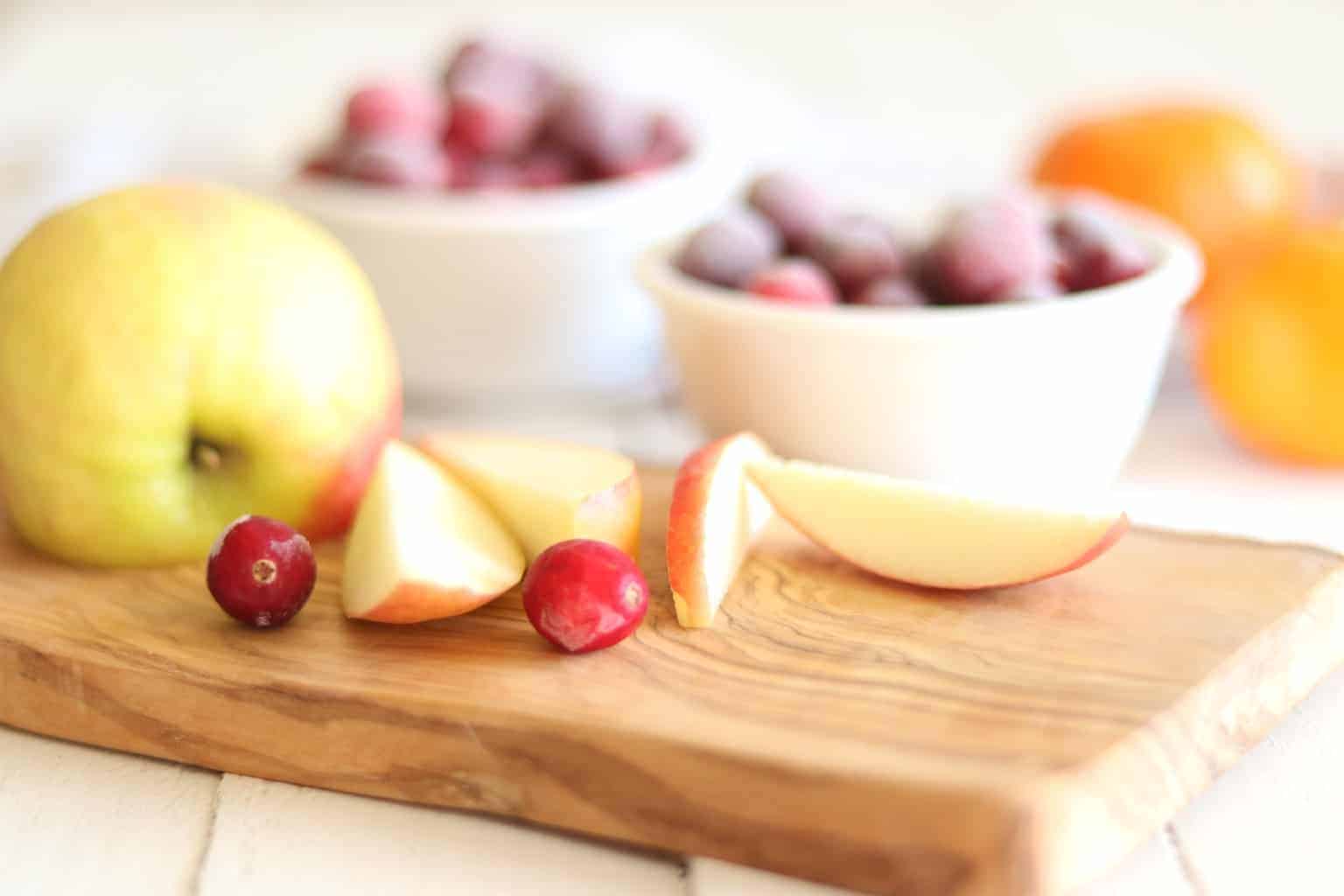 Sliced apples, cranberries, and clementine's on tables.