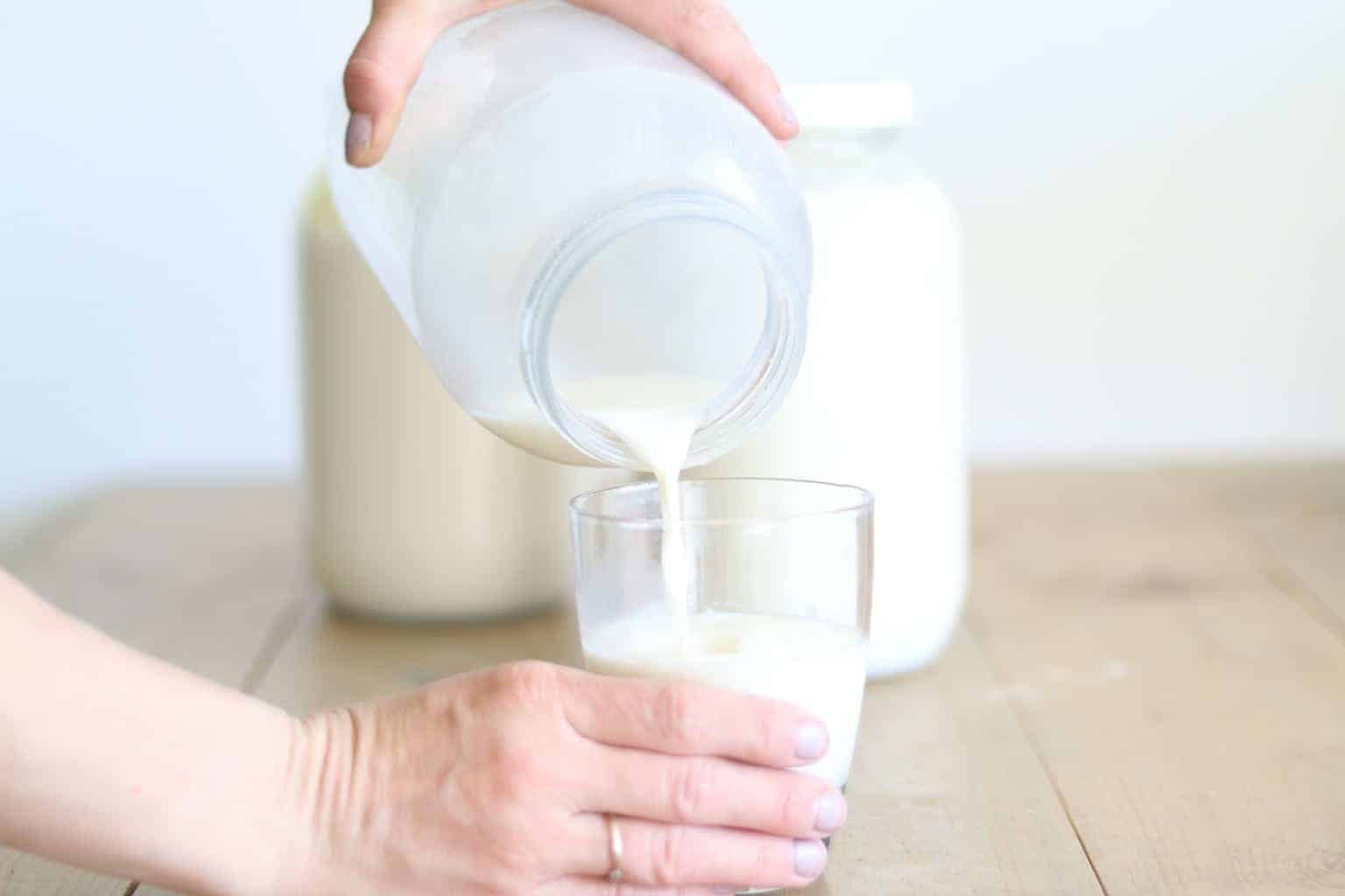 Purring raw milk from half gallon jar into glass cup.