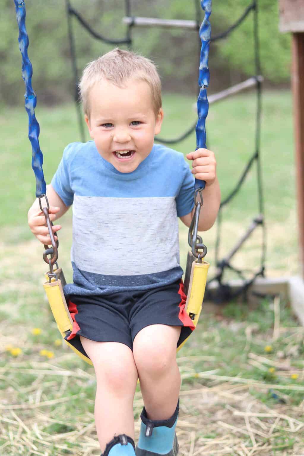 Little boy swinging on a swing.