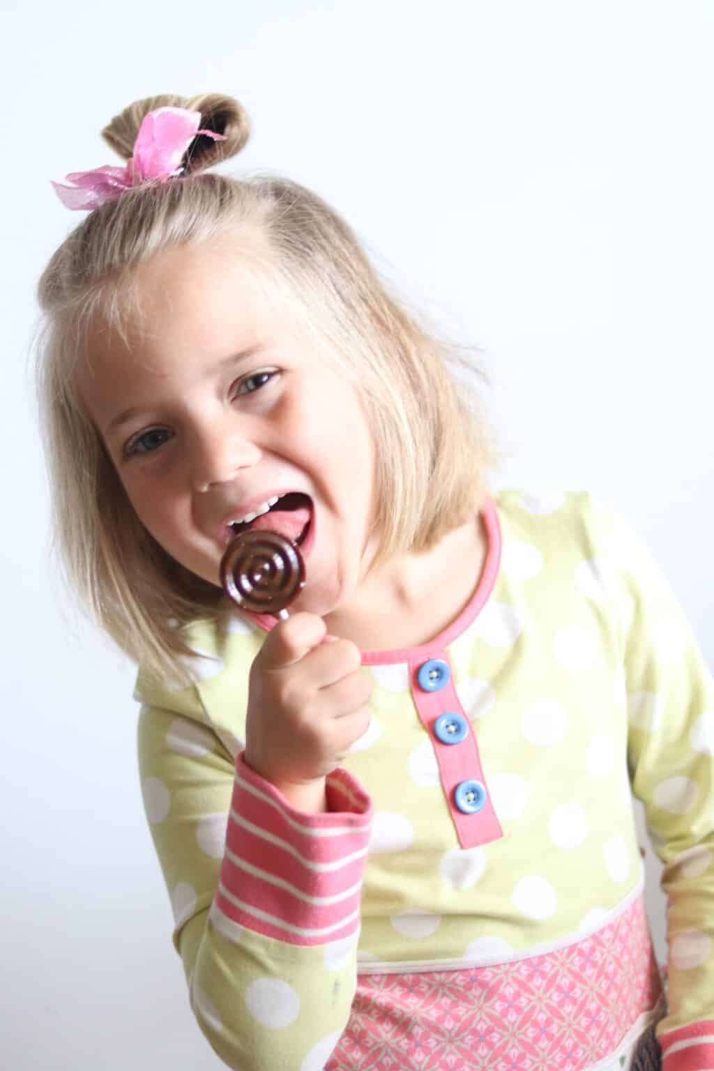 Little girl licking a healthy lollipop.