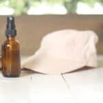 sunglasses hat and spray bottle on white table
