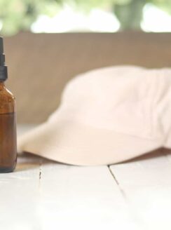 sunglasses hat and spray bottle on white table