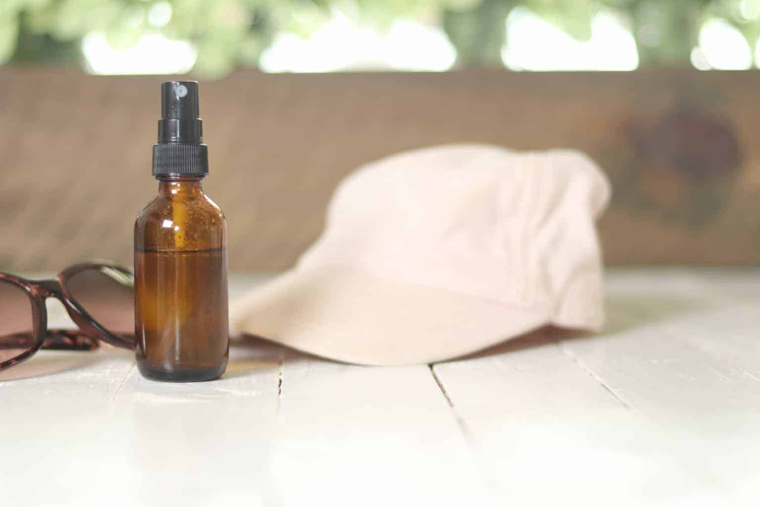 Sunglasses, hat and homemade spray bottle on white table.