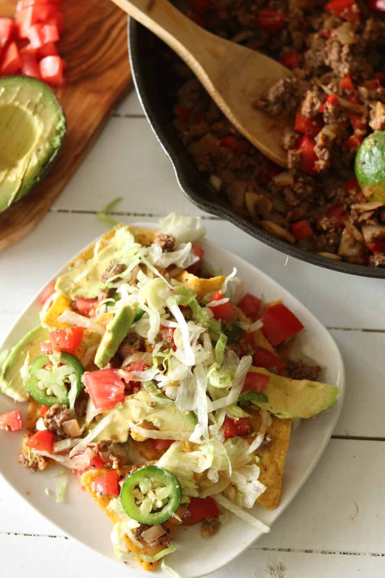 Homemade nachos topped with jalapeños, tomatoes, and avocado. 