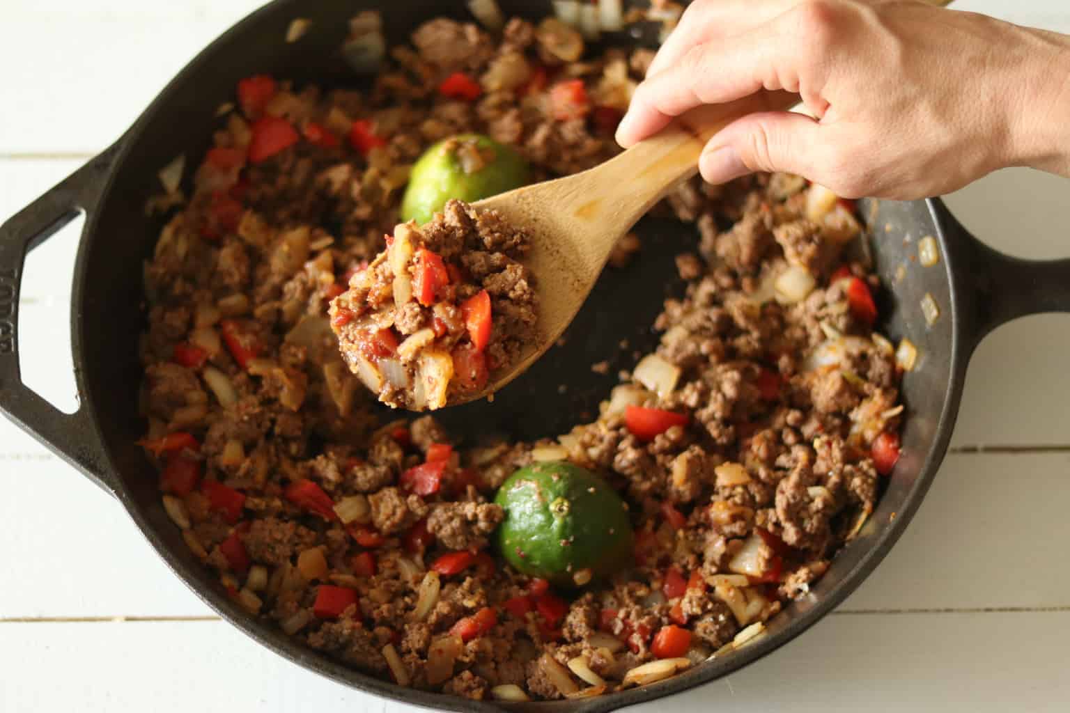 Paleo taco meat in cast iron skillet with chopped peppers and onions.