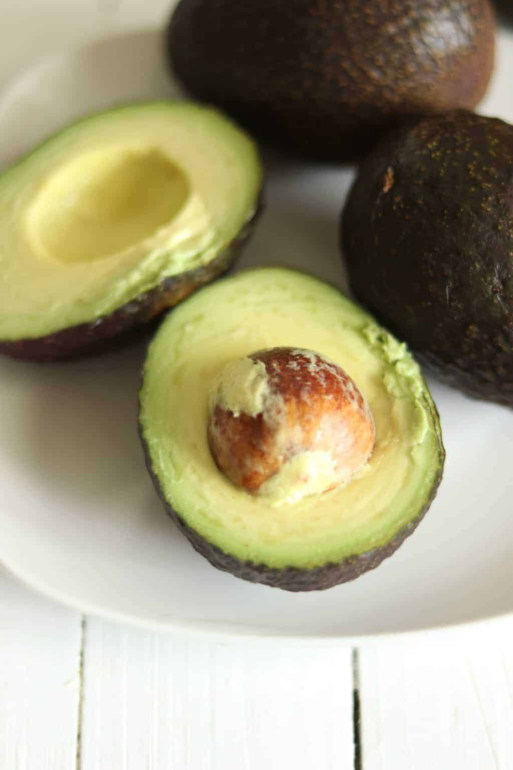 Fresh avocados on white plate.