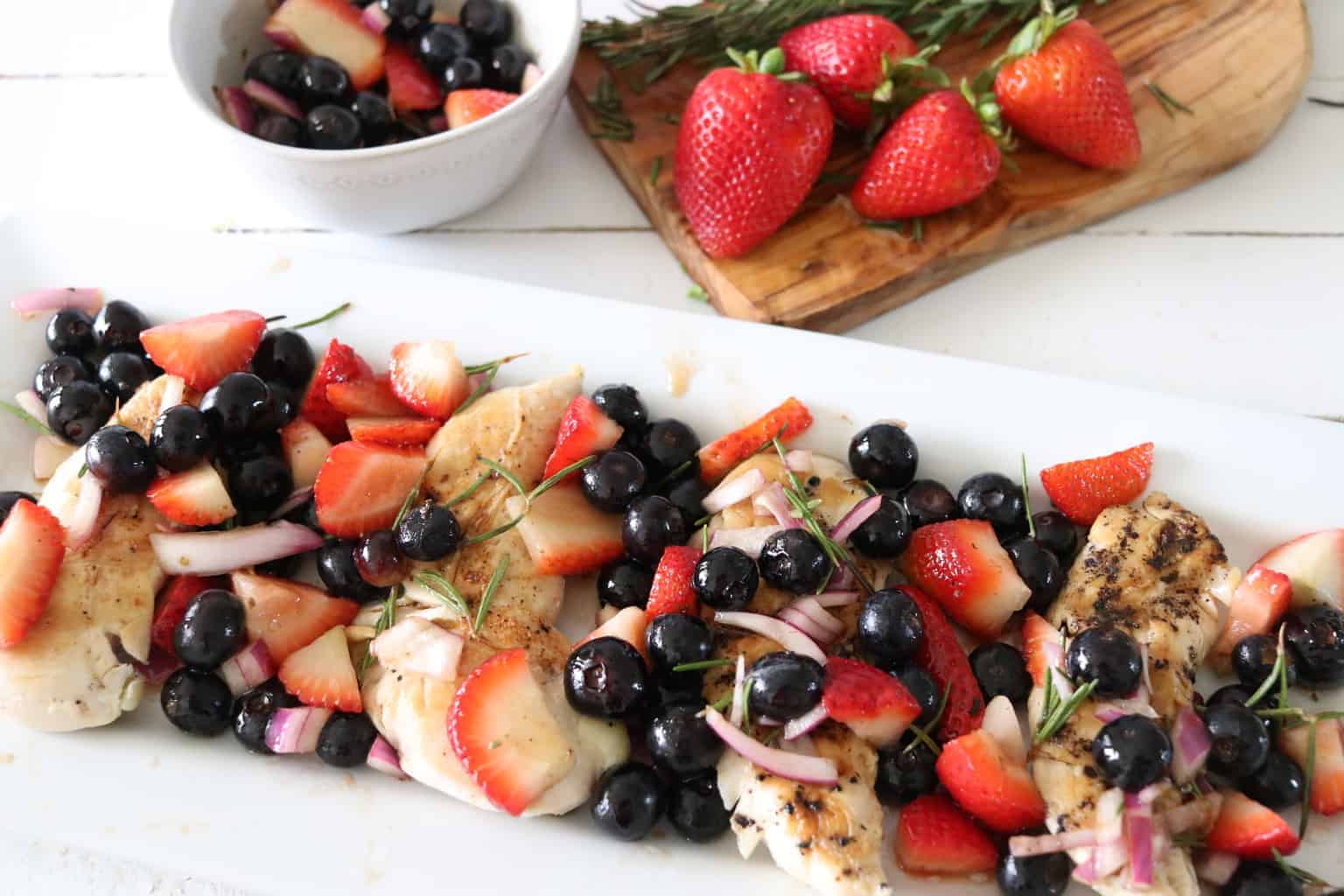 Berry salsa over chicken on white plate on table.