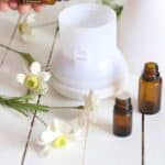 Adding lemongrass essential oil to a white petal diffuser.