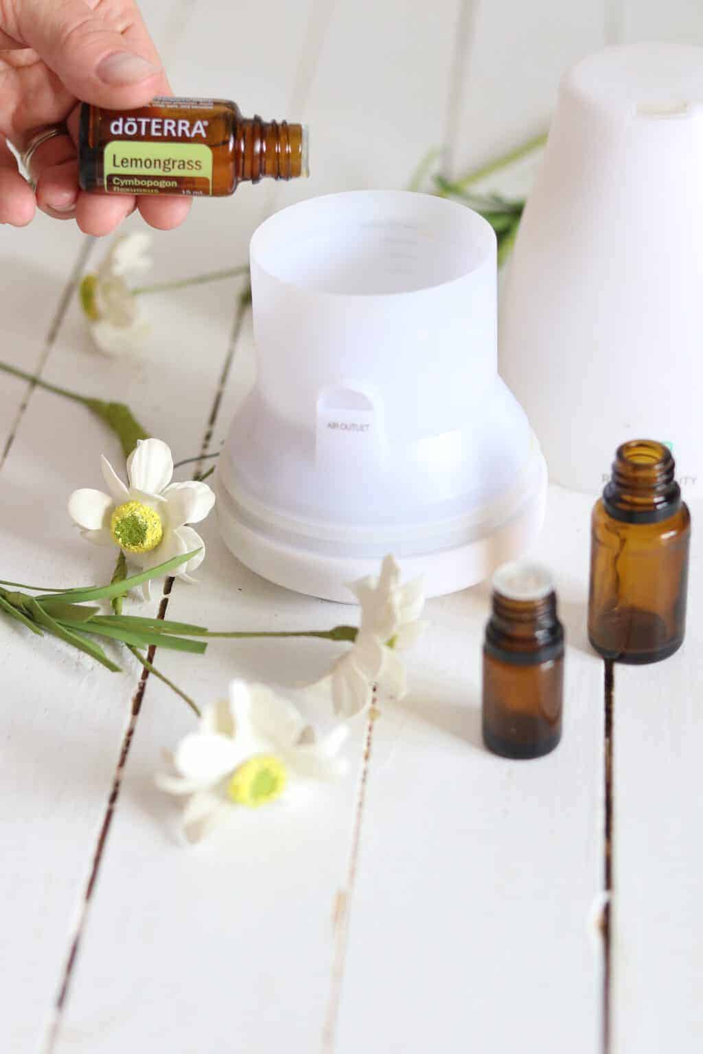Lemongrass essential oil, diffuser, flowers, and amber bottles on table.