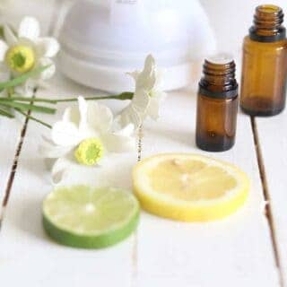 Summer essential oils with lemon and lime slices on a white shiplap table.