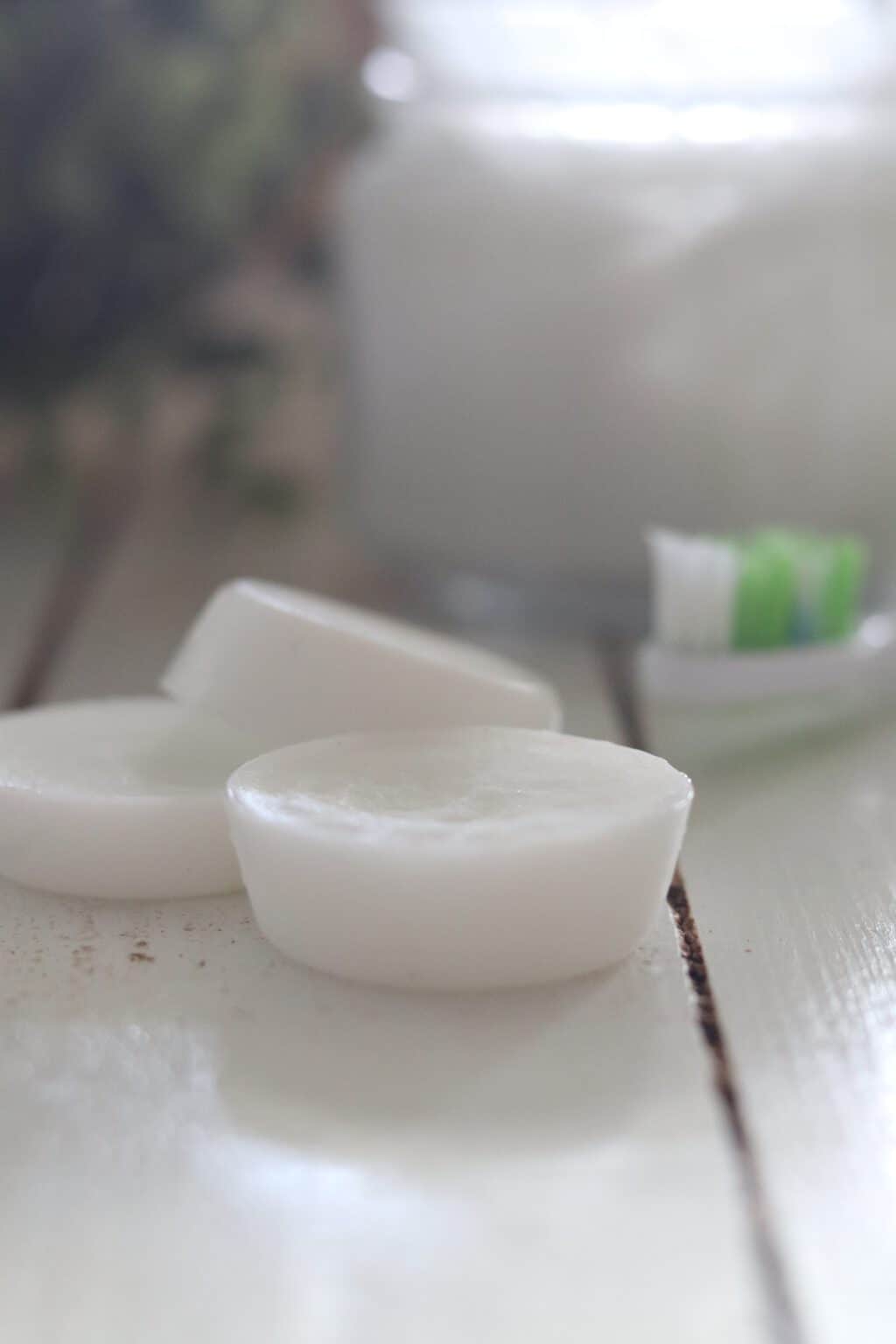 Coconut oil pulling pods, toothbrush, and mason jar on wooden table. 