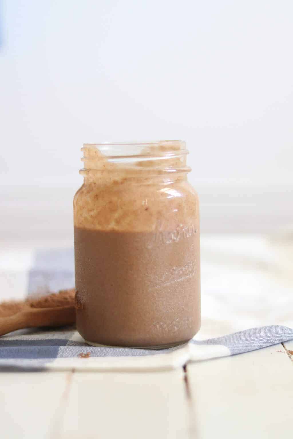 Healthy peanut butter chocolate ice cream in quart size mason jar on white shiplap.