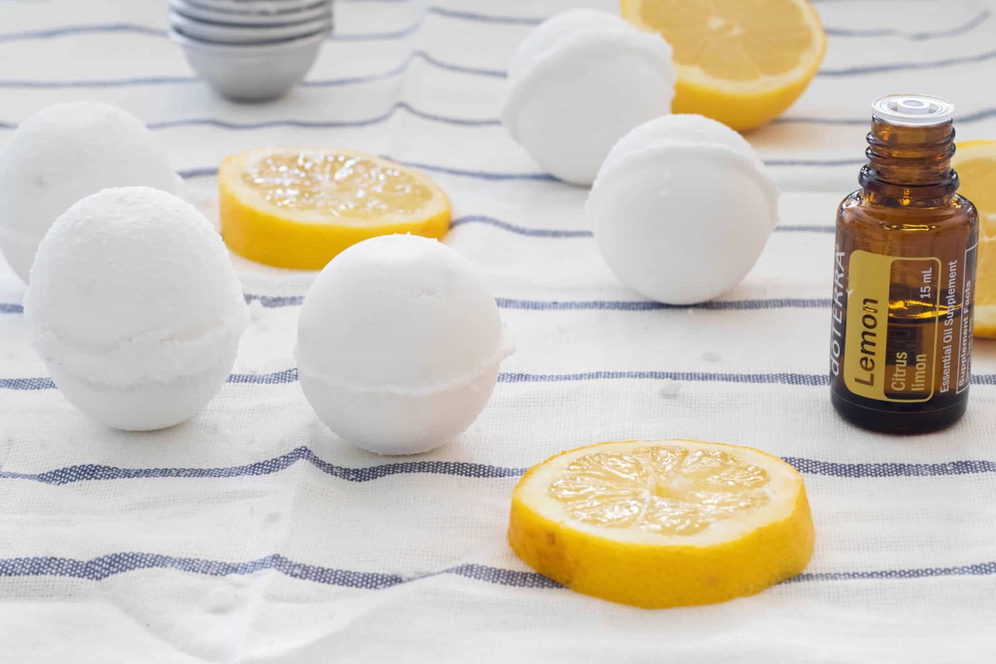 Homemade toilet cleaning bombs next to lemon slices and lemon essential oil.