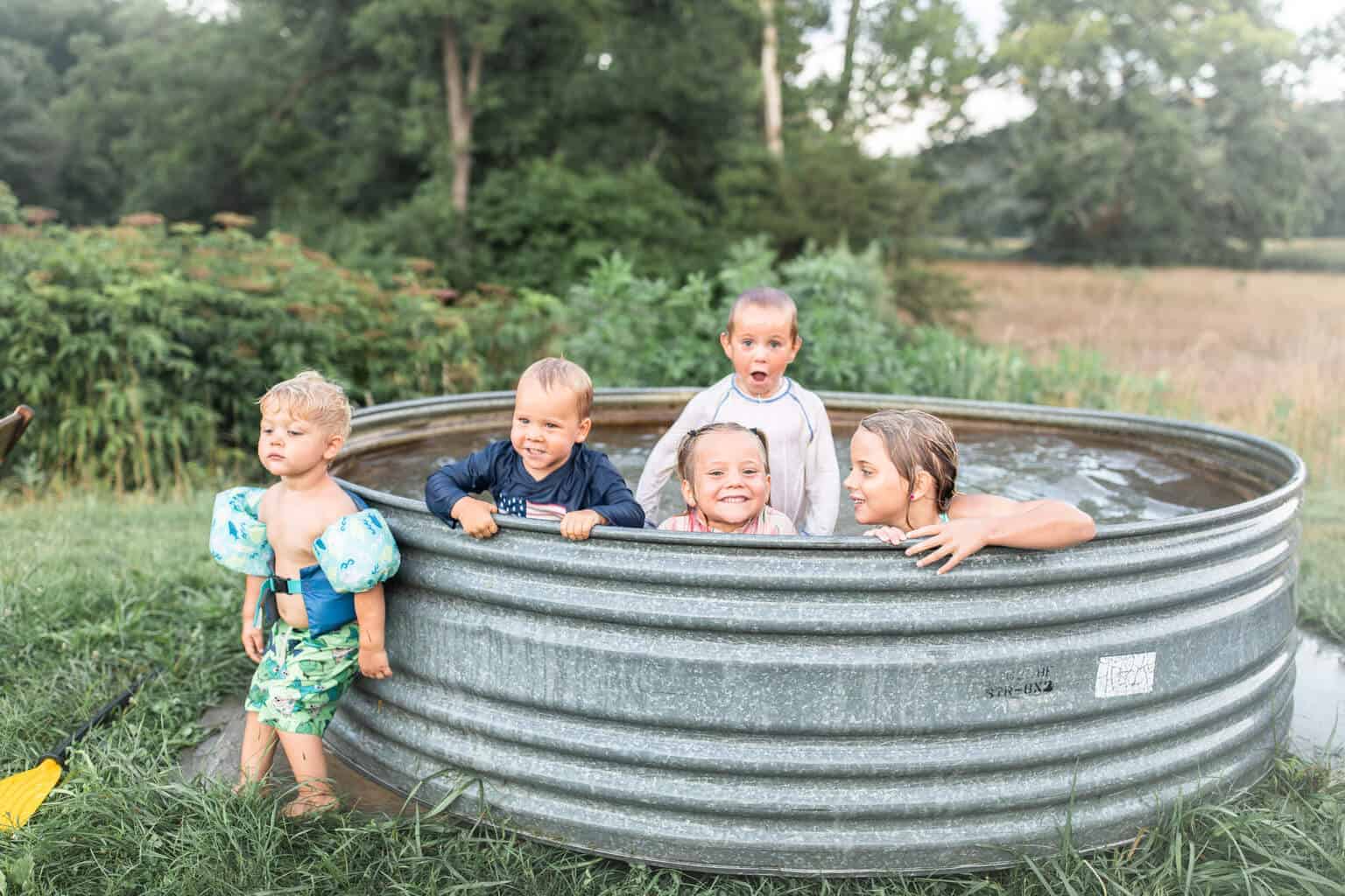 Kids swimming in a tank pool outside.