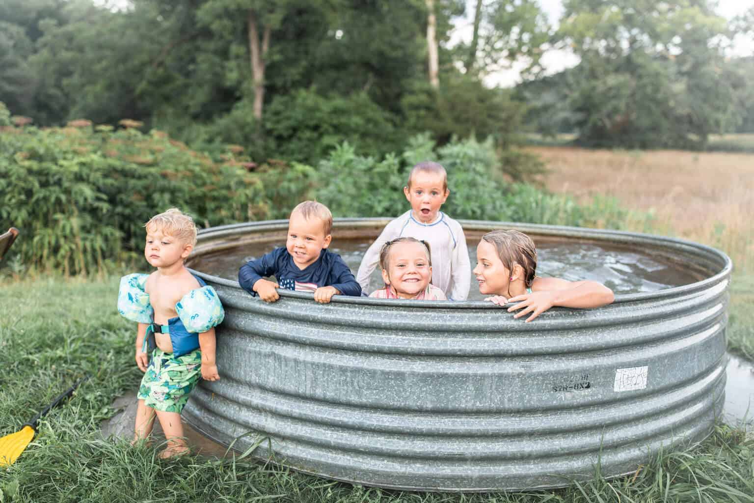 Kids swimming in a tank pool outside.