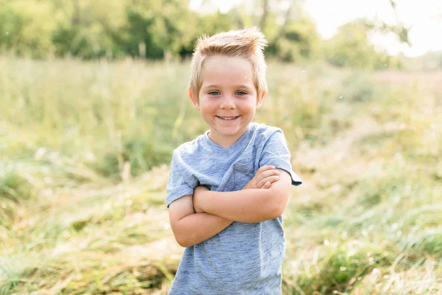 Picture of little boy in blue shirt in a open field.