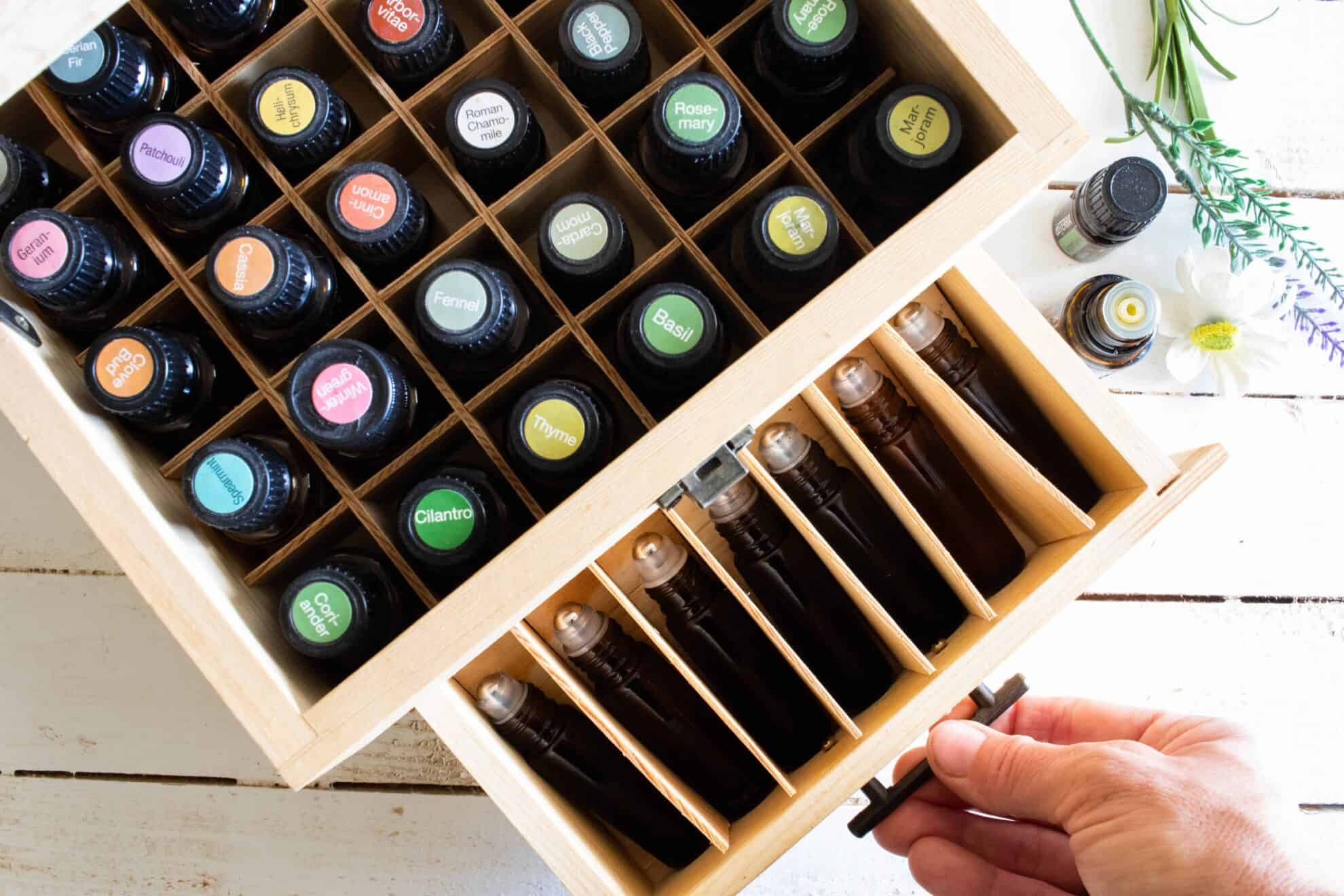 Essential oil roller blends in wooden storage box on white shiplap.