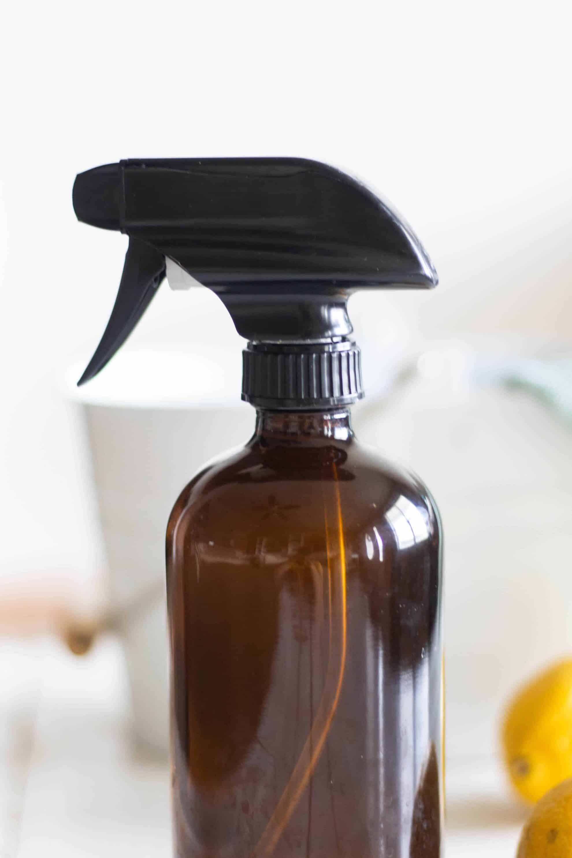 Brown glass spray bottle with toxic-free house cleaner on white background.