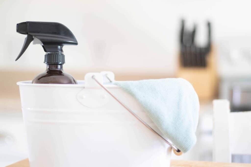 All-purpose cleaner spray in a white cleaning caddy with a green microfiber towel.