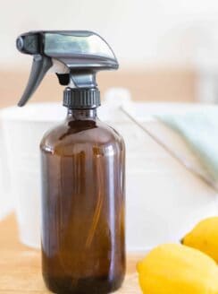 amber glass spray bottle lemons and cleaning lady on table