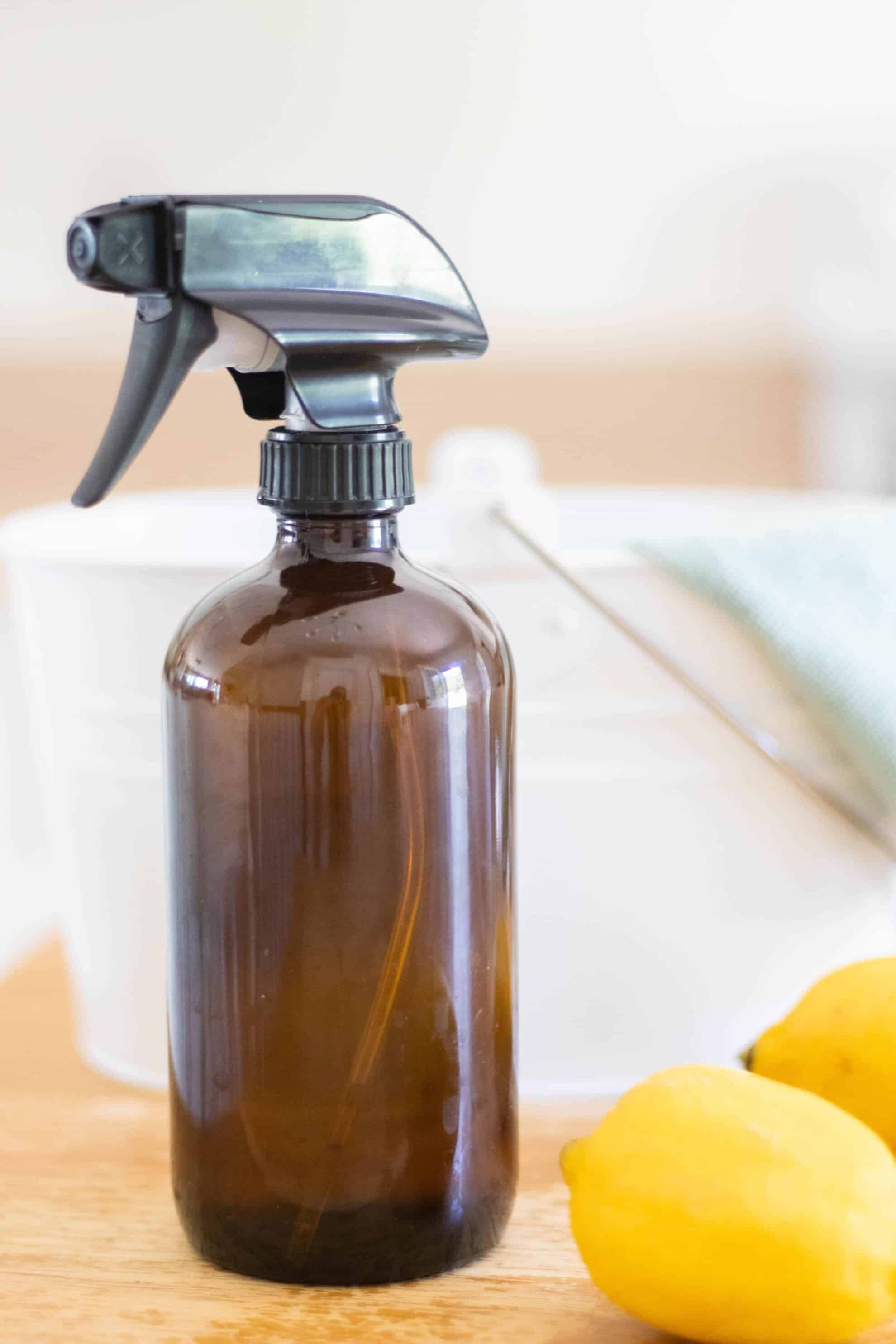 All-purpose cleaner in amber glass spray bottle on table with fresh lemons.