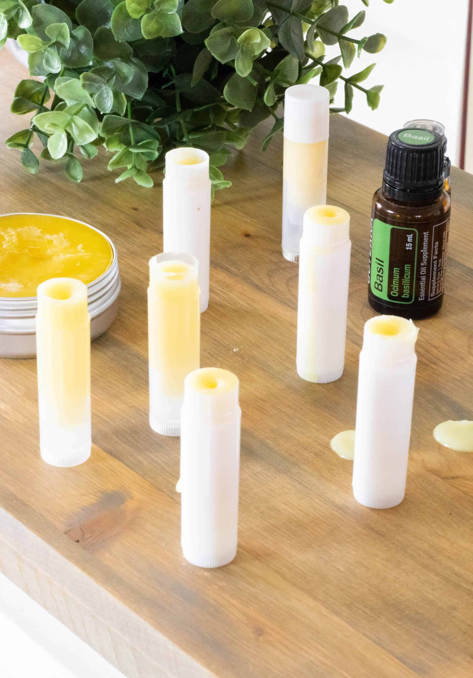 Homemade bug bite balm on wooden table with essential oil bottle.