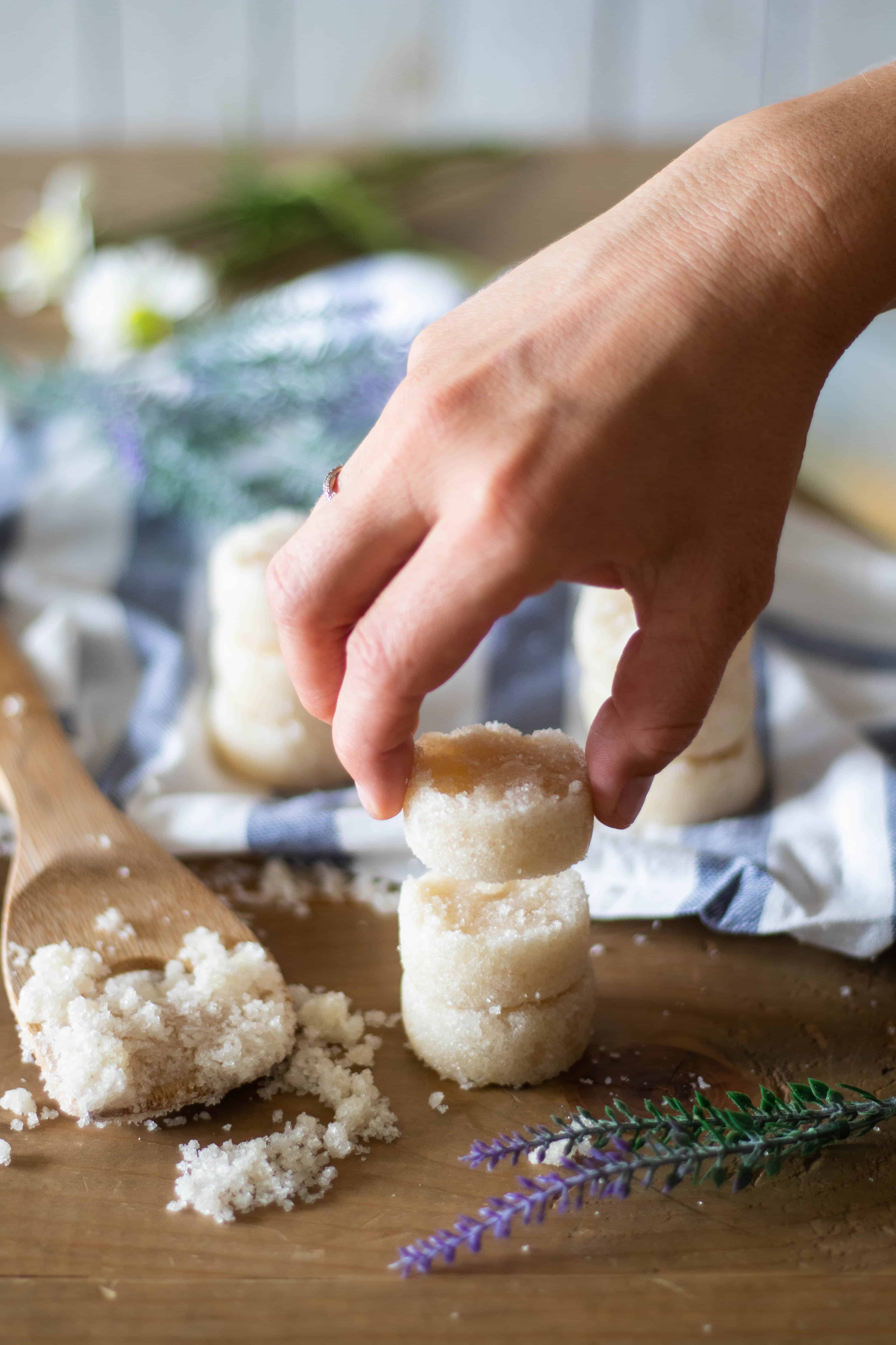 Healthy sugar scrub bars with stripped towel and flowers surrounding it.