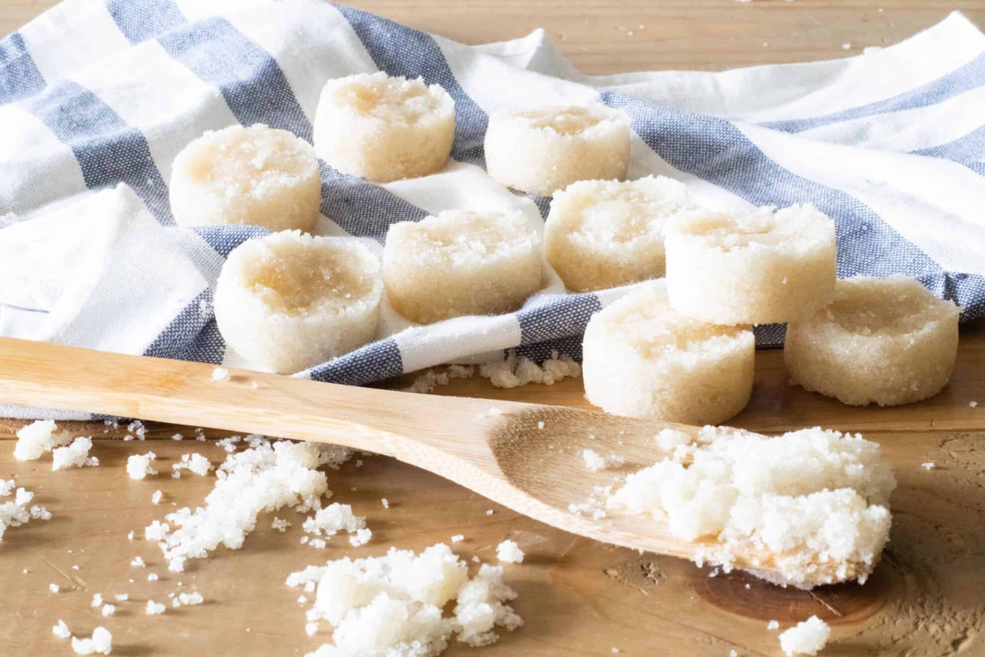 Homemade mini sugar scrub bars on wooden table with stripped towel.