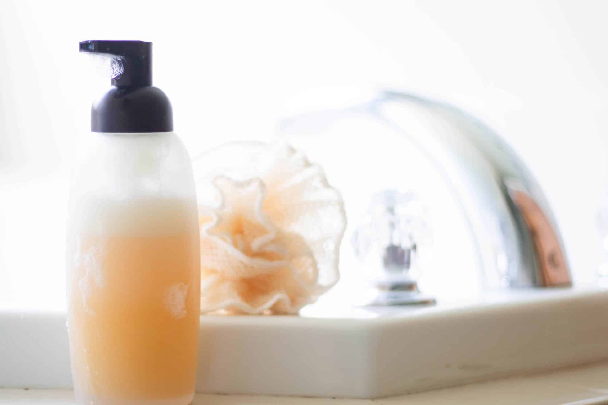 Foaming honey body wash next to sink.