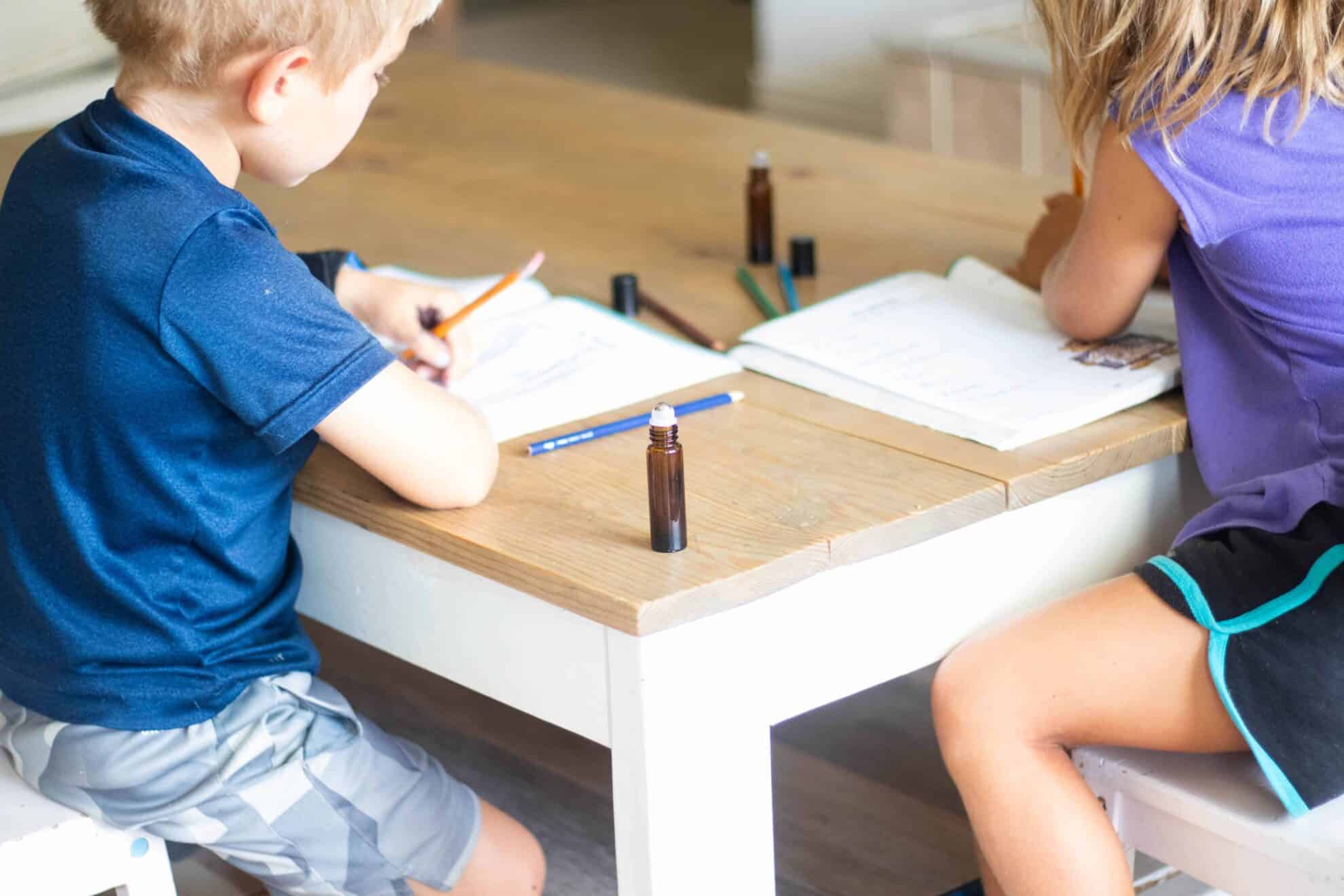 Two little kids sitting at coffee table working on homework.