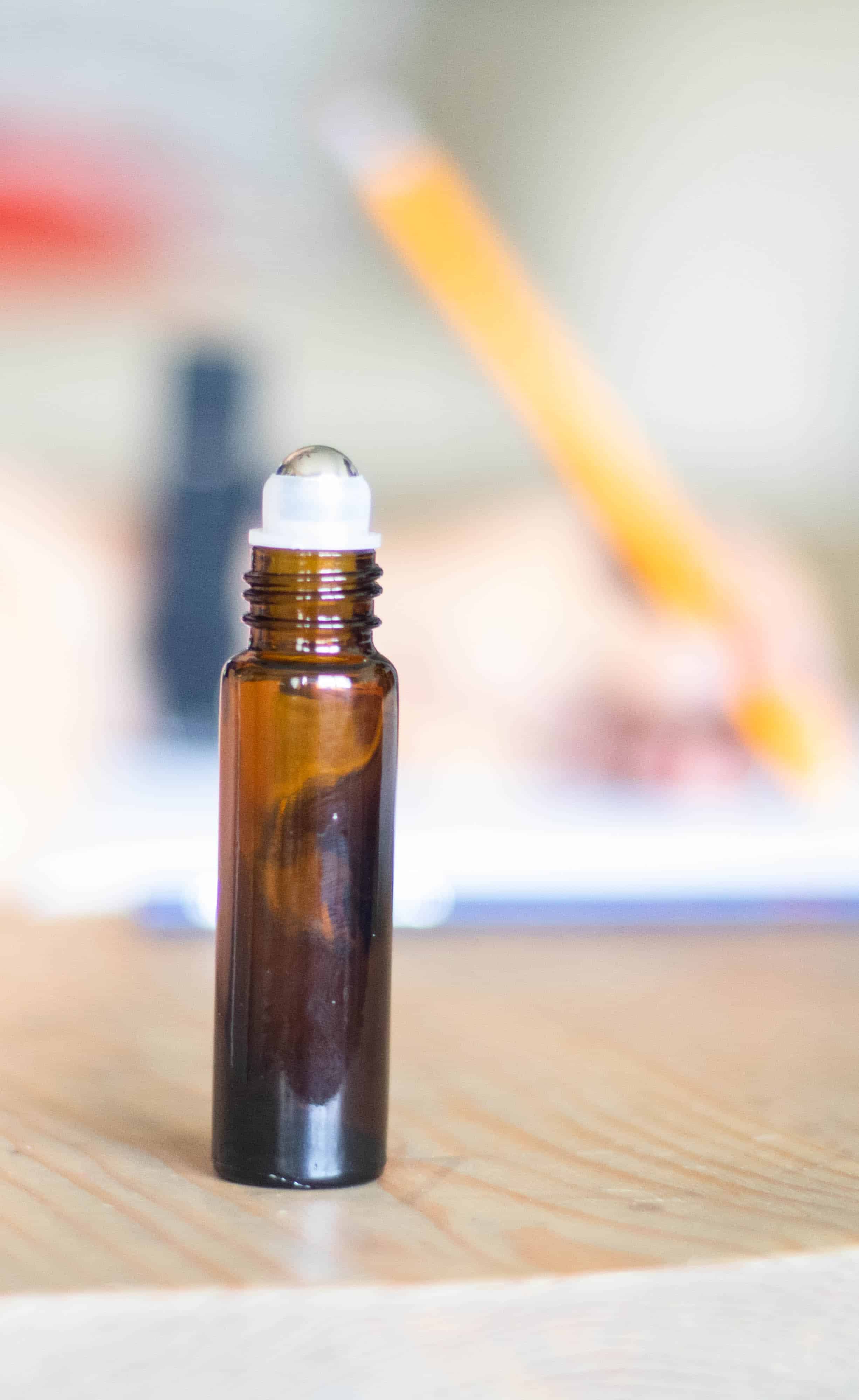 Amber essential oil roller bottle on wooden table.