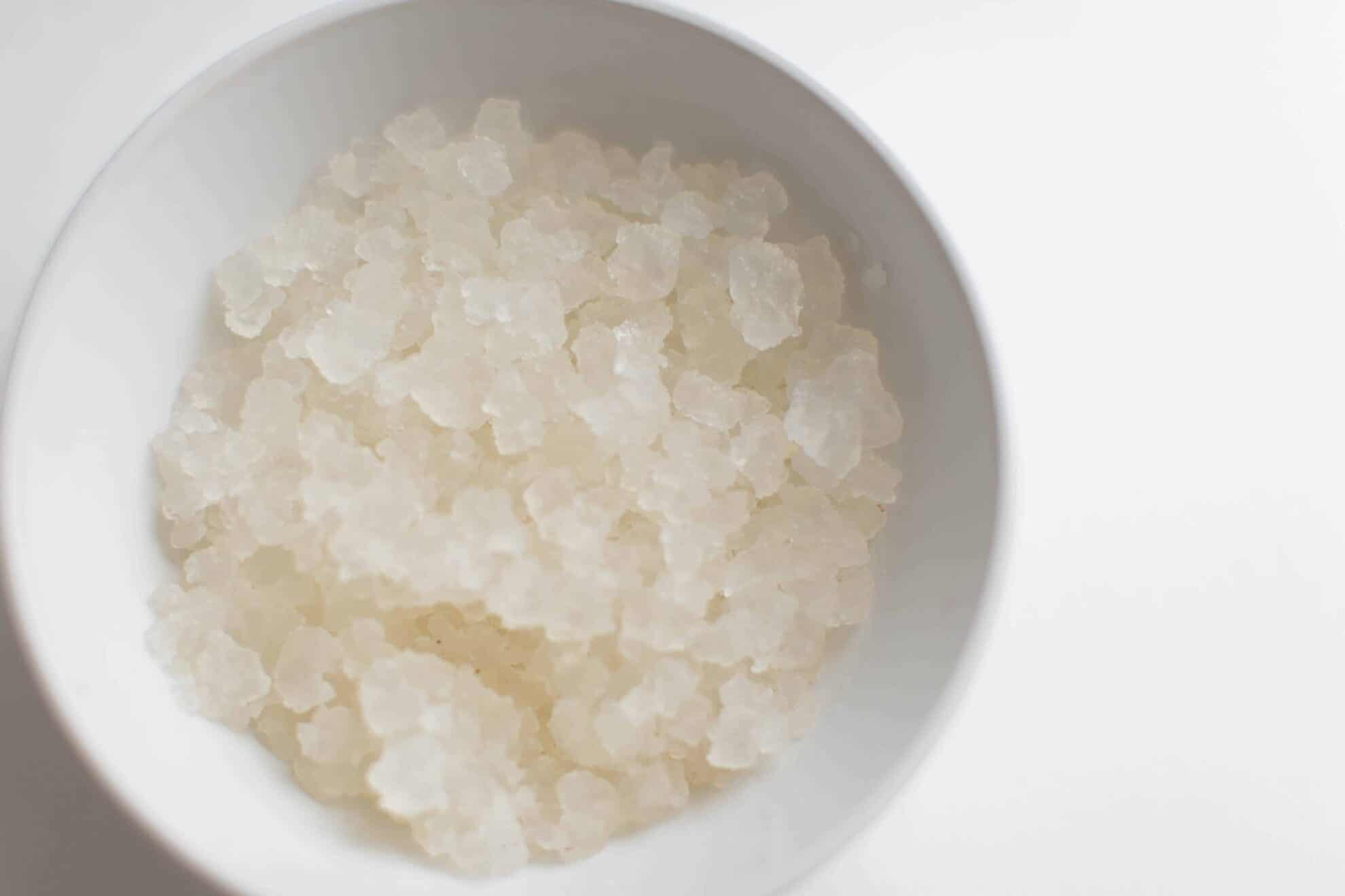 Water kefir grains in white bowl on white table.