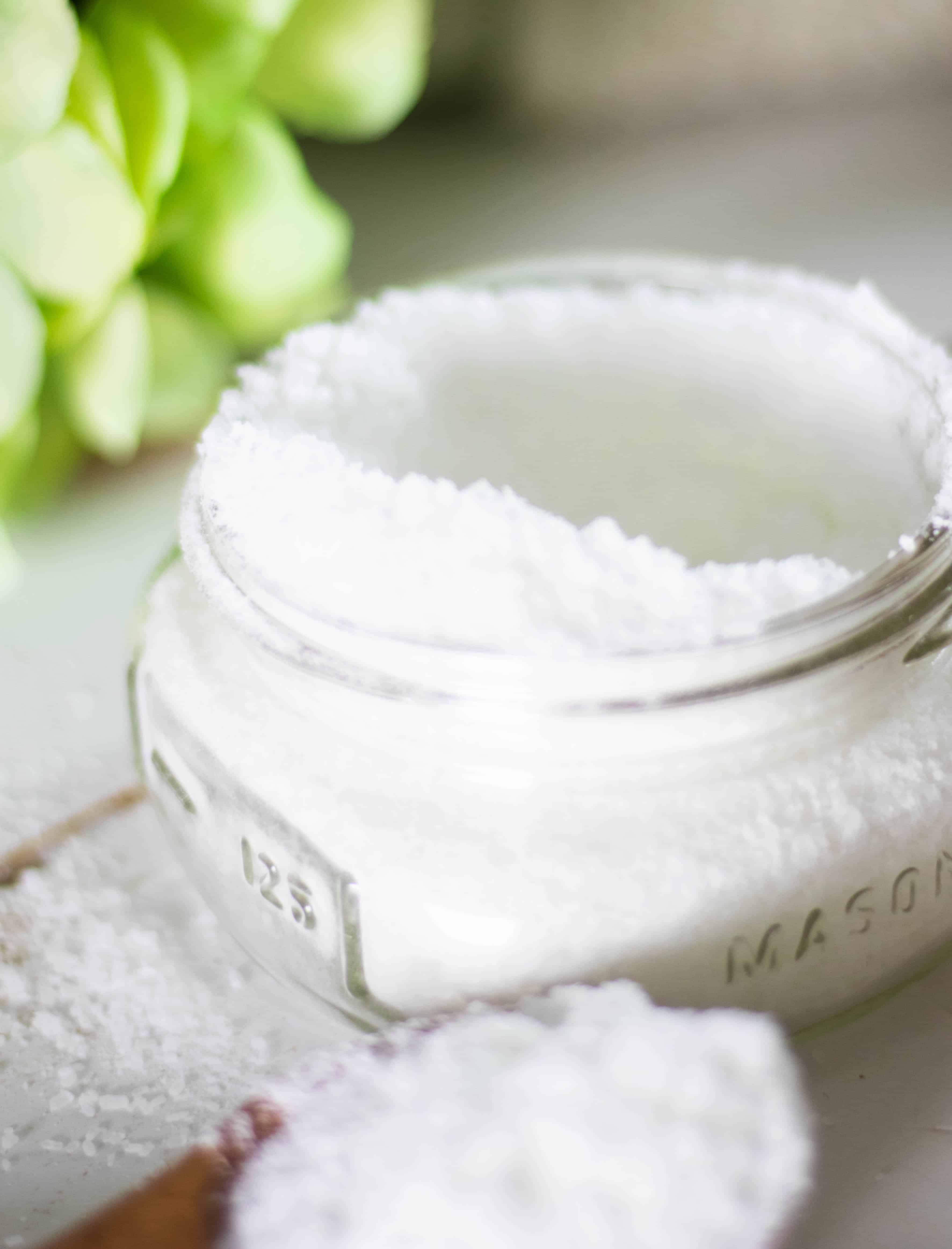 Wide mouth mason jar filled with powder laundry sent boaster on white table.