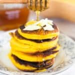 pumpkin pancakes on floral plate honey being poured over them