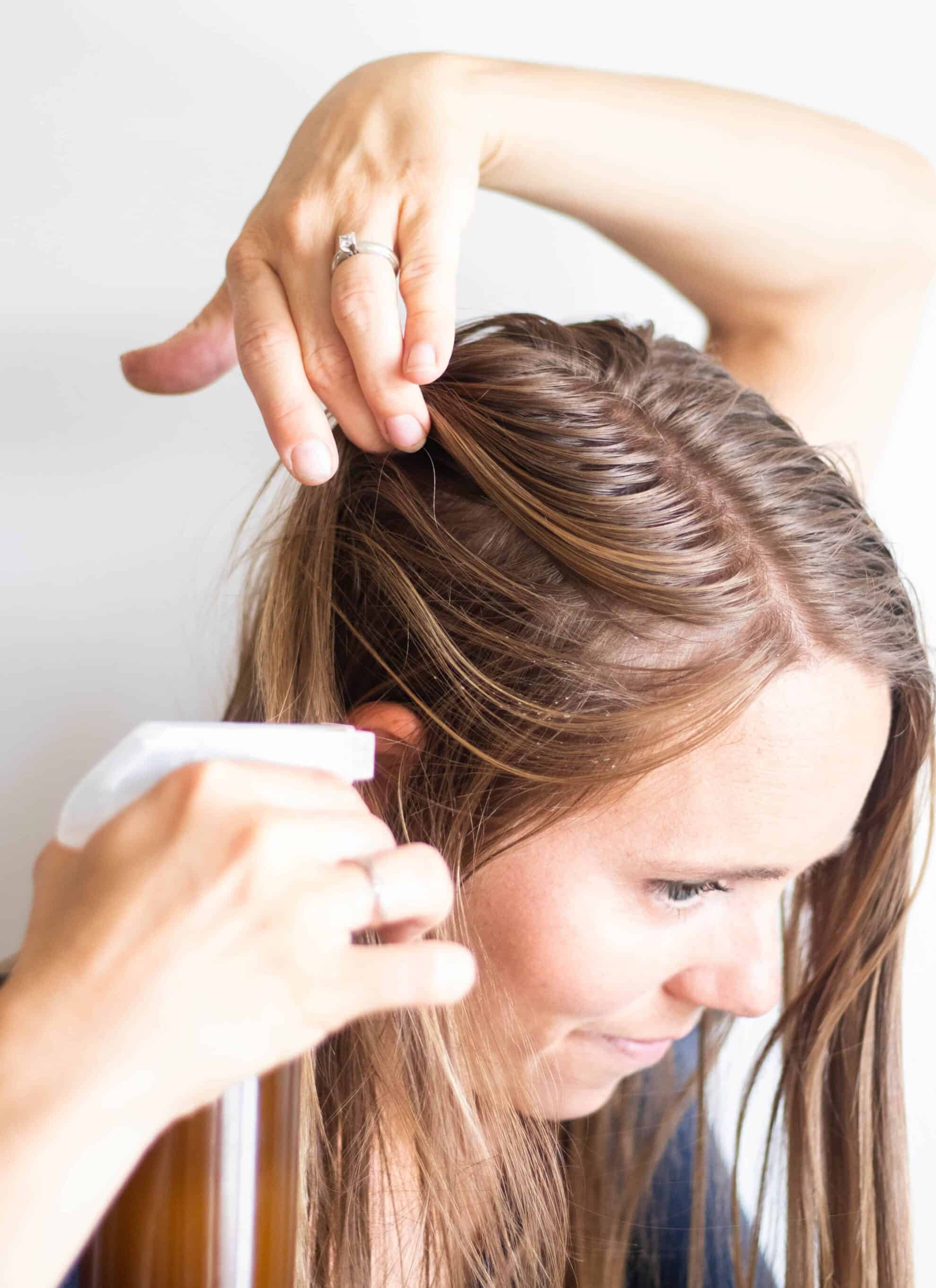 Side view of women spraying her hair with dry shampoo.