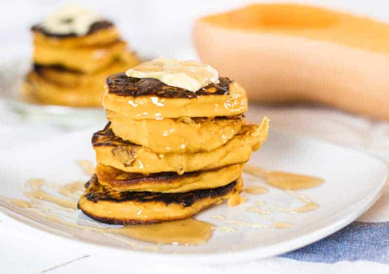 Healthy pumpkin pancakes stacked on white plates.