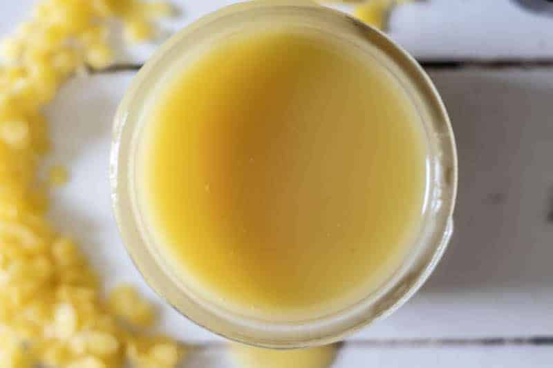 Yellow homemade vapor rub in small mason jar on wooden table.