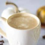 latte with pumpkin and cinnamon sticks in background