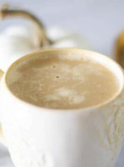 latte with pumpkin and cinnamon sticks in background