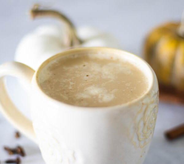 latte with pumpkin and cinnamon sticks in background