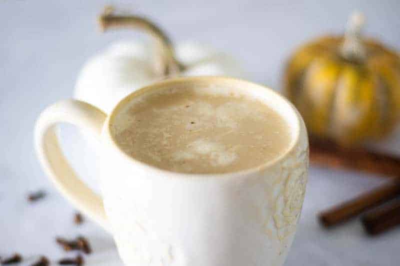 Paleo latte with pumpkin and cinnamon sticks in background.